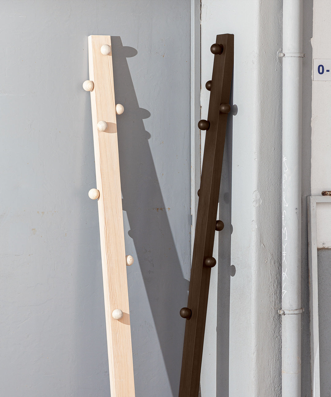 Solid wood hanger by João Xará with a sturdy, natural finish, designed for hanging clothes in a minimalist style.