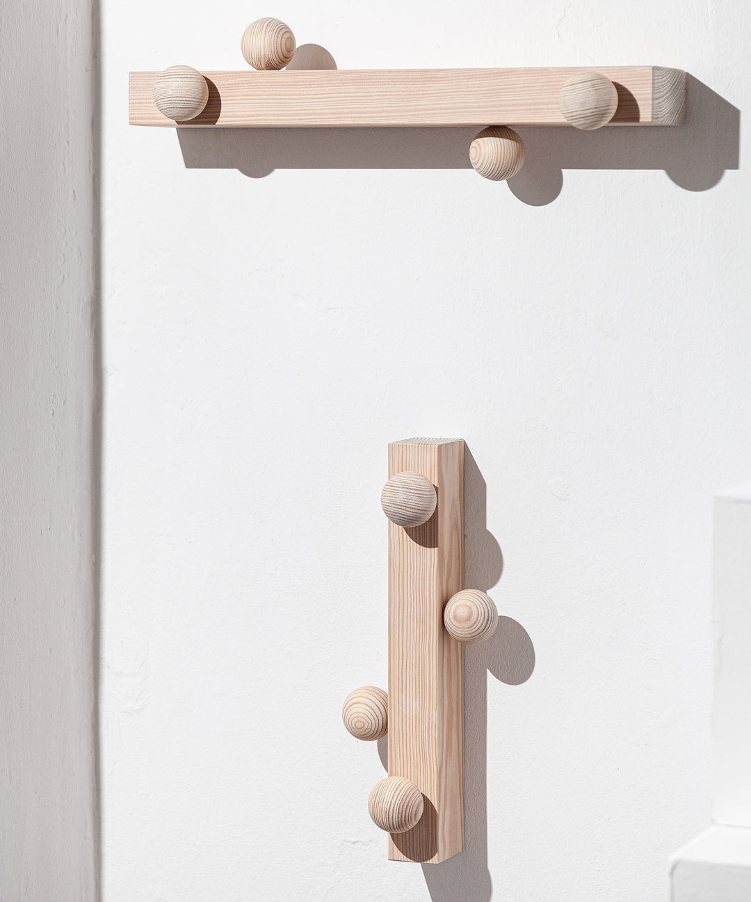 Solid wood João Xará Burly hanger hanging on a clothing rack, showcasing durable craftsmanship and natural wood finish.