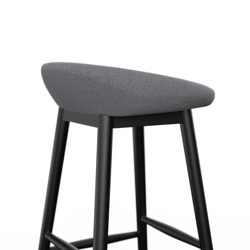 Porventura CAKE stools combine black-painted ash wood frames with dark grey fabric upholstery, revealing a quiet elegance through subtle contrasts in texture and tone.