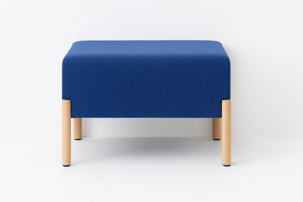 Porventura COD ottoman, upholstered in blue Camira fabric with beech wood legs, combining a cushioned square form with an understated contemporary design.