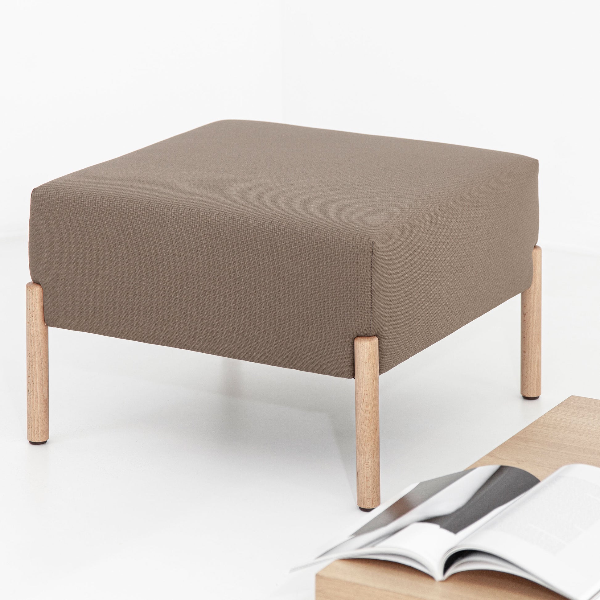 O pufe Porventura Cod, acessório para sofá, apresenta um design elegante e moderno em tecido neutro, perfeito para a decoração da sala de estar.