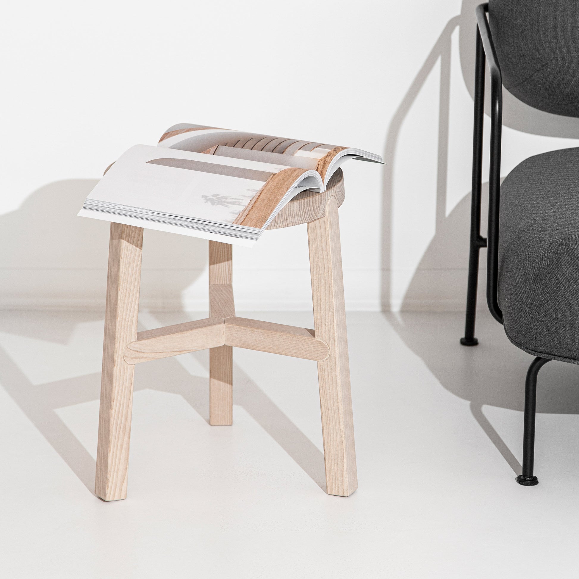 O banco Porventura Glyph, com um design elegante e moderno, apresenta curvas suaves e uma estética minimalista, exibido num ambiente bem iluminado.