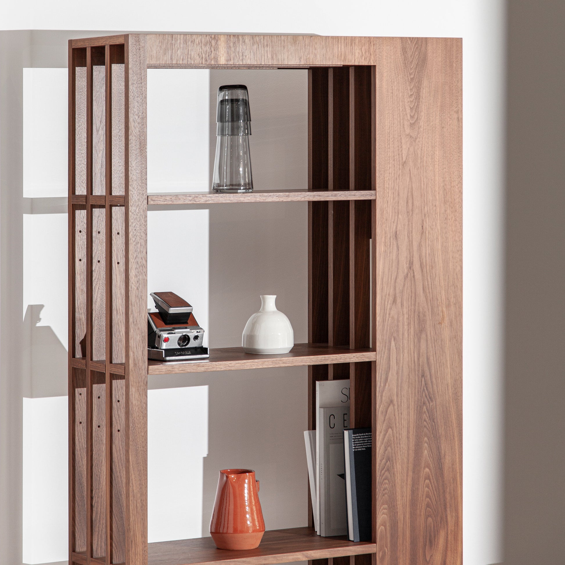A estante Porventura, denominada Rule, apresenta um design elegante com várias prateleiras horizontais e suportes verticais robustos.